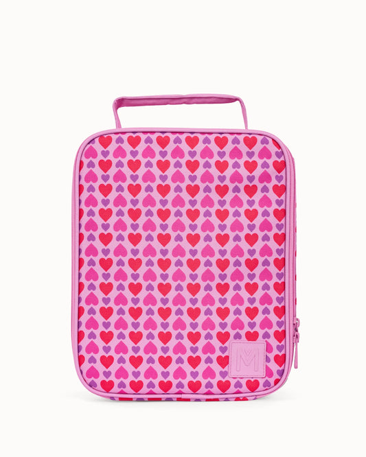 A pink and purple patterned lunch bag with a repeating heart design, featuring a top handle and a small embossed logo patch on the bottom right.